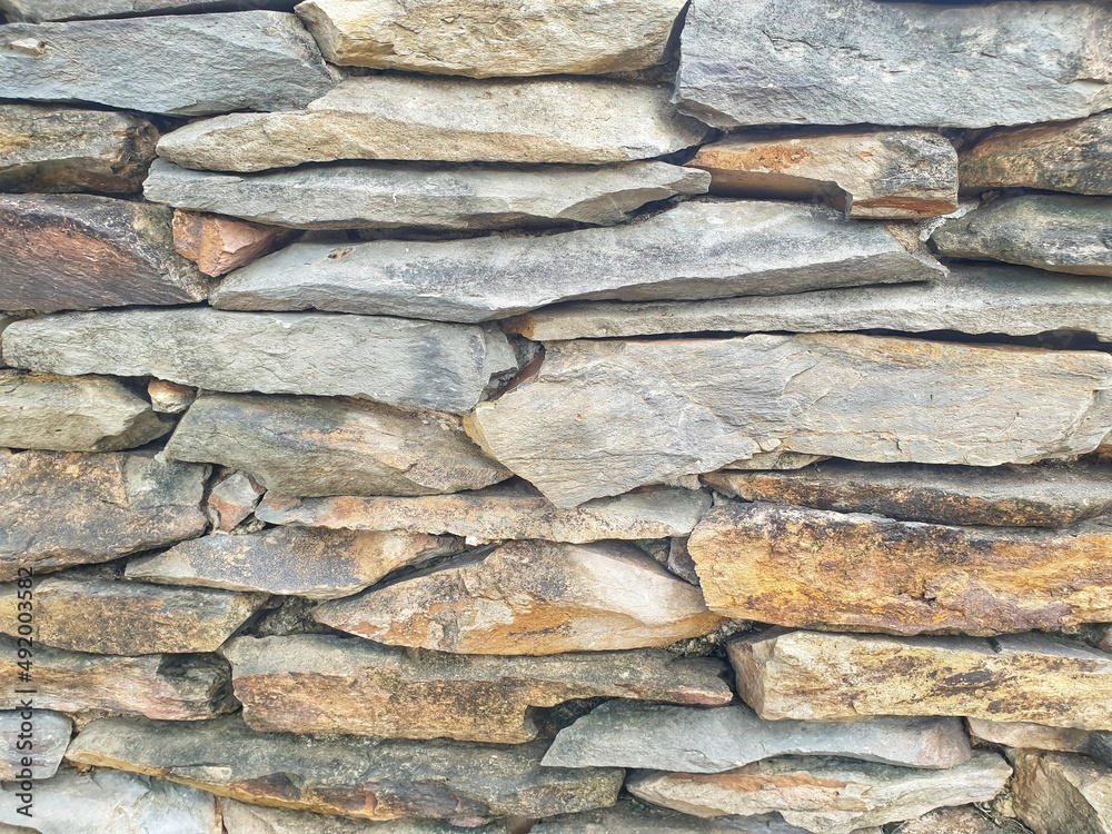 stone wall texture. The stones are stacked together to form a wall.abstract background. Weathered stained old stone brick wall,red brick wall gradually wear away. stone wall texture. The stones are stacked together to form a wall.abstract background. Weathered stained old stone brick wall,red brick wall gradually wear away.