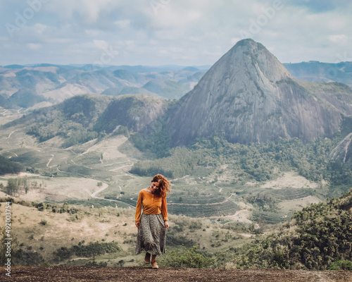 mulher com blusa amarela caminhando com montanhas ao fundo em Pancas, Espírito Santo photo