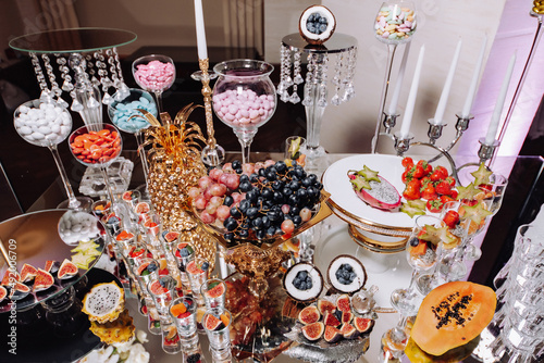 Luxury candy bar on golden wedding. Candy bar decorated by flowers standing of festive table with deserts, and cakes, strawberry tartlet, cupcakes and macarons. Wedding. Reception Tartlets