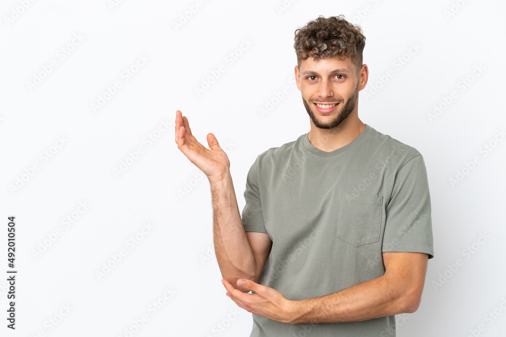 Young caucasian handsome man isolated on white background extending hands to the side for inviting to come