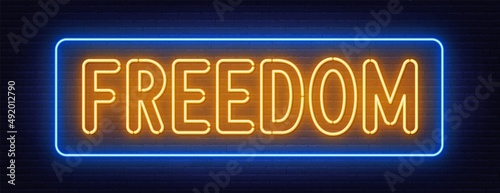 Freedom neon sign on brick wall background.