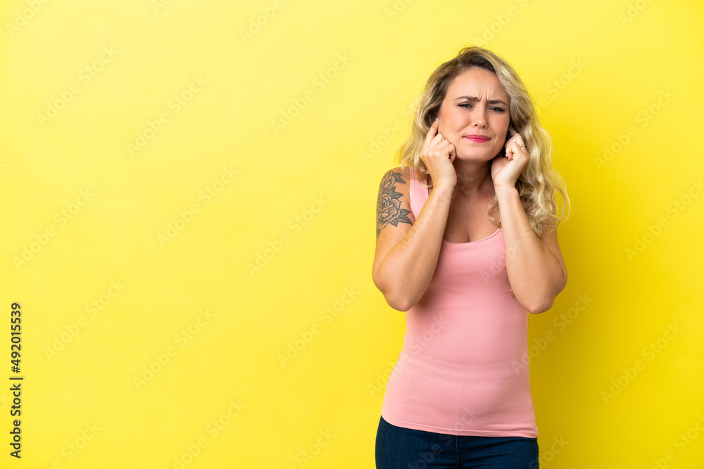 Young Brazilian woman isolated on yellow background frustrated and covering ears Young Brazilian woman isolated on yellow background frustrated and covering ears