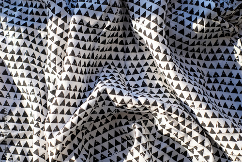 Fabric with a black white geometry, textile abstract background with sunlight