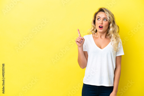 Young Brazilian woman isolated on yellow background thinking an idea pointing the finger up