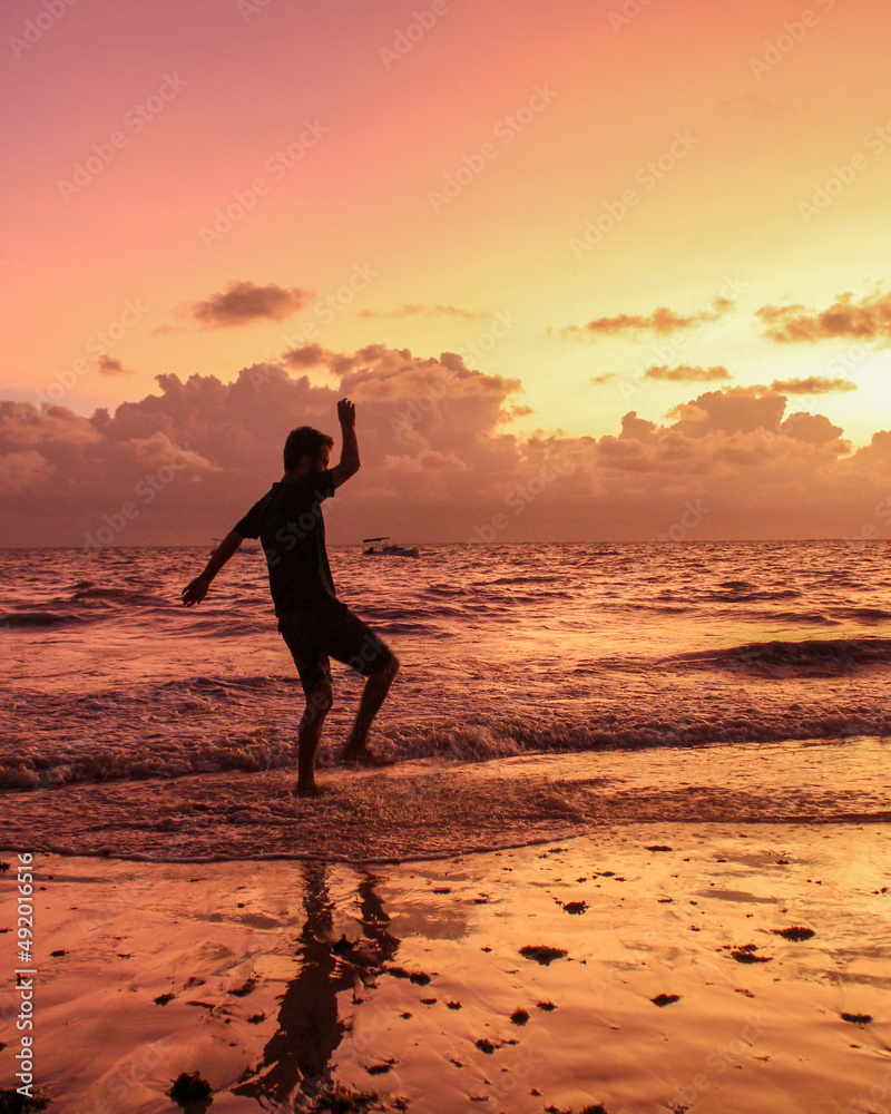 silhueta de homem não identificado pulando ondas durante o nascer do sol na Ponta do Seixas, Paraíba