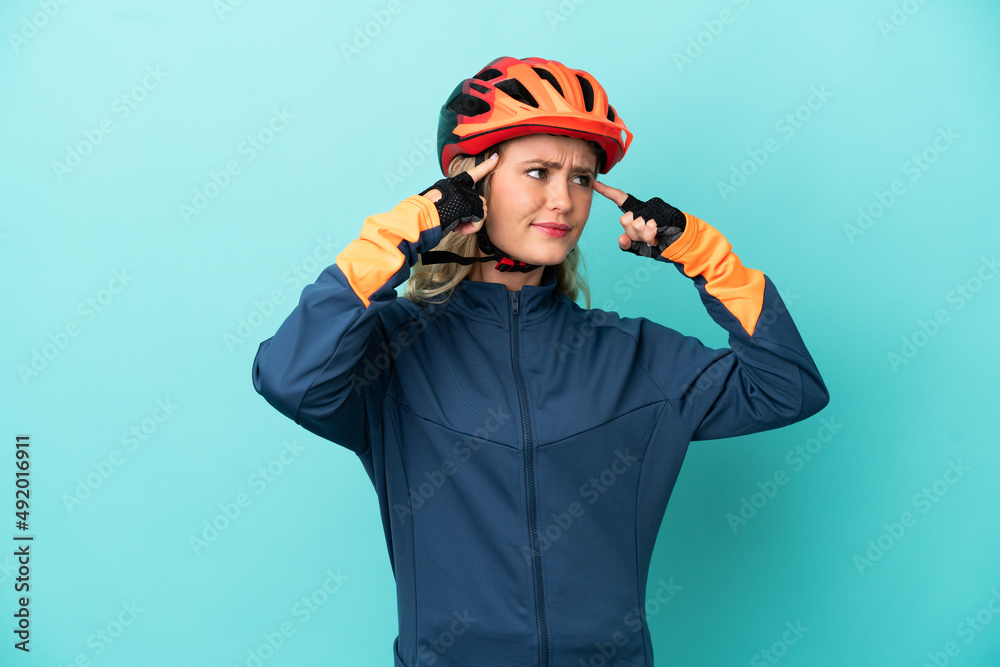 Fototapeta premium Young cyclist woman isolated on blue background having doubts and thinking