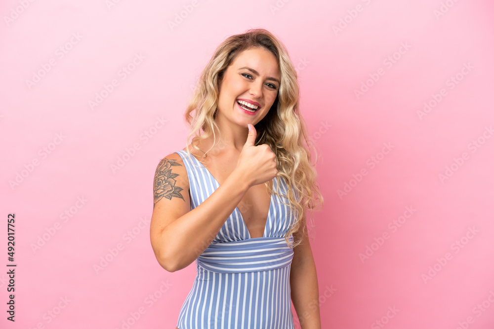 Young Brazilian woman in swimsuit in summer holidays isolated on pink background with thumbs up because something good has happened Young Brazilian woman in swimsuit in summer holidays isolated on pink background with thumbs up because something good has happened