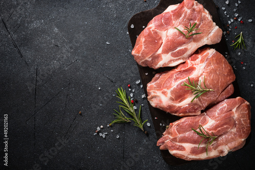 Raw meat. Fresh meat steaks with herbs and spices at black background. Close up image. Top view with space for design.