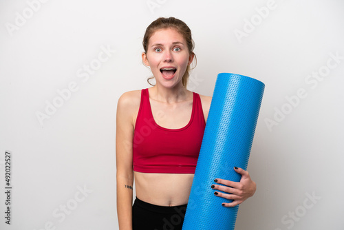 Young sport English woman going to yoga classes while holding a mat isolated on white background with surprise facial expression