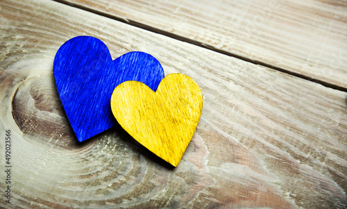 two  wooden hearts in colors of Ukrainian flag on the wooden table