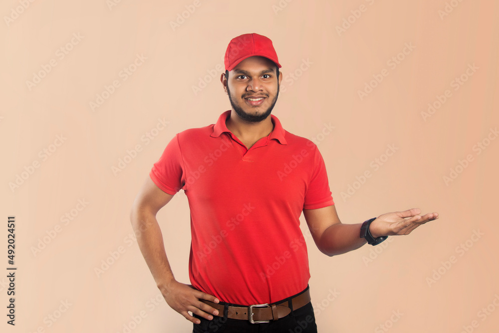 Confident young delivery man standing with raised hand isolated on Color Background