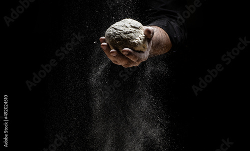 the chef sprinkles flour through a sieve  Powdery flour flying into air. chef hands with flour in a freeze motion of a cloud of flour midair