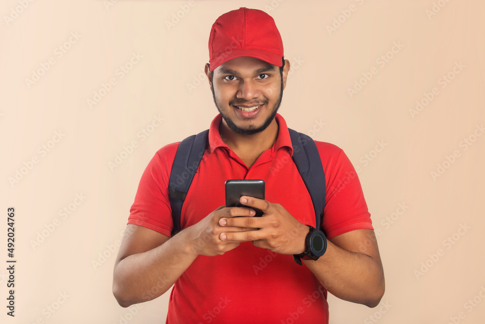 Confident young delivery man looking at camera with mobile phone Confident young delivery man looking at camera with mobile phone