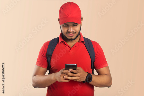 Confident young delivery man holding mobile phone © paltu