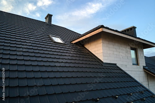 Closeup of house roof top covered with ceramic shingles. Tiled covering of building