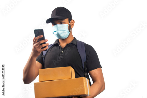 Portrait Of Young Delivery Man wearing face mask Holding parcel with mobile phone