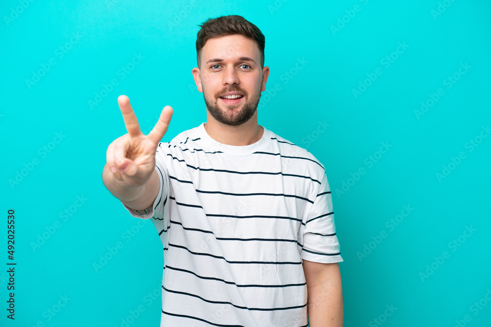Young caucasian man isolated on blue background smiling and showing victory sign Young caucasian man isolated on blue background smiling and showing victory sign