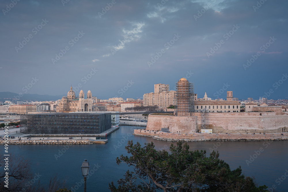 Sunset and night view over Cathedral, Fort and Mucem buildings in Marseille harbour, France