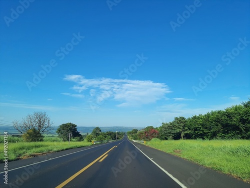 Asphalt road with green grass and hills and a beautiful blue Ceu. Sao Paulo, Brazil.