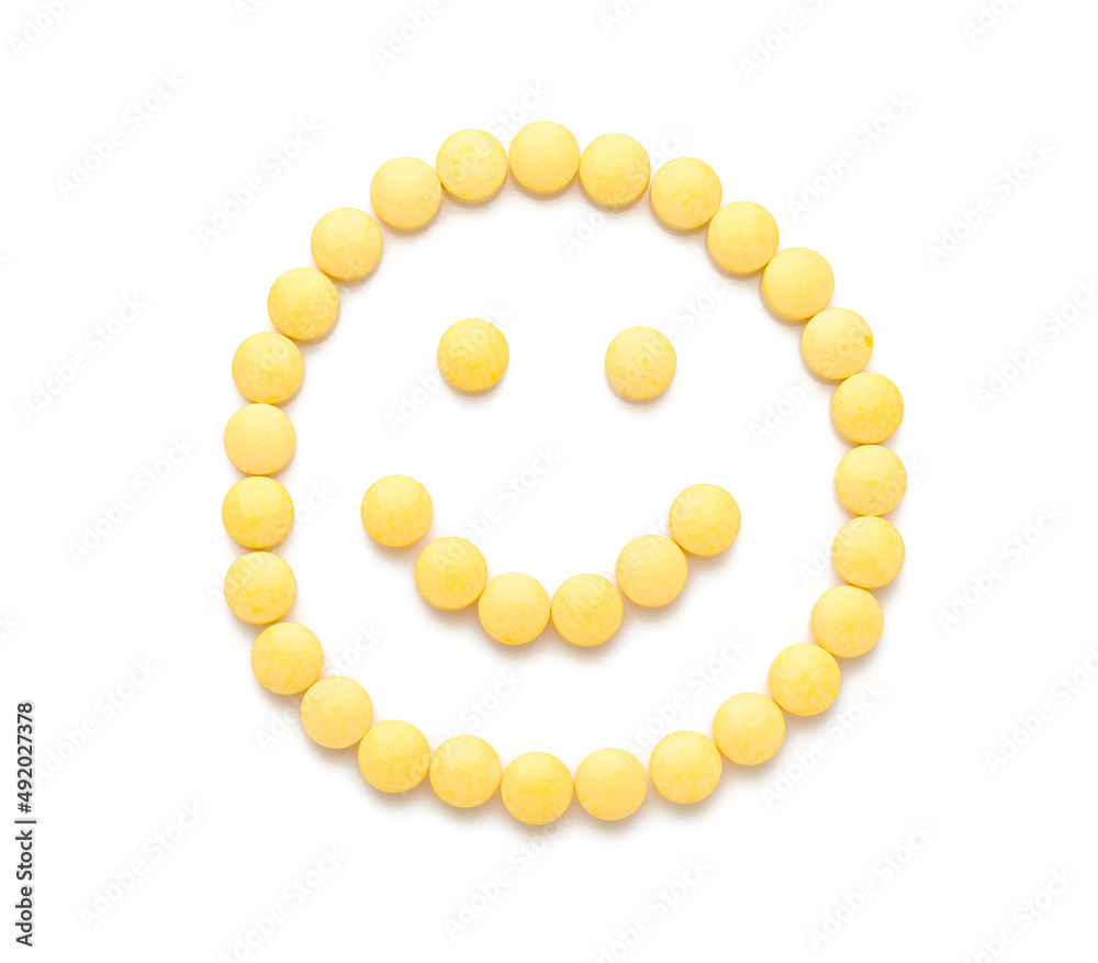 Obraz premium Happy smiley made of yellow pills on white background