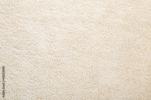 Beige new fluffy home carpet background. Closeup. Empty place for text. Top down view.