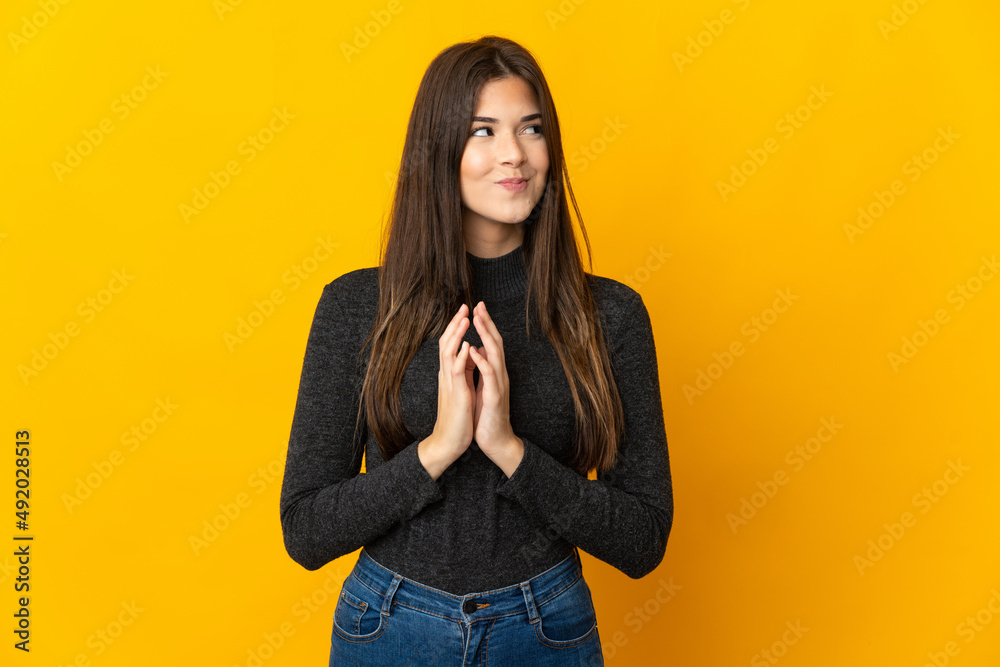 Teenager Brazilian girl isolated on yellow background scheming something Teenager Brazilian girl isolated on yellow background scheming something