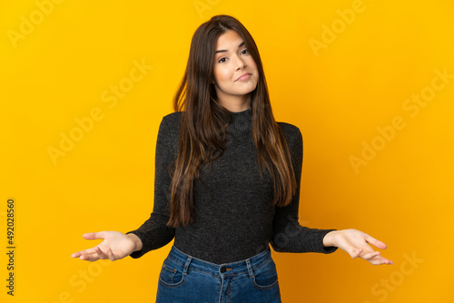 Teenager Brazilian girl isolated on yellow background having doubts