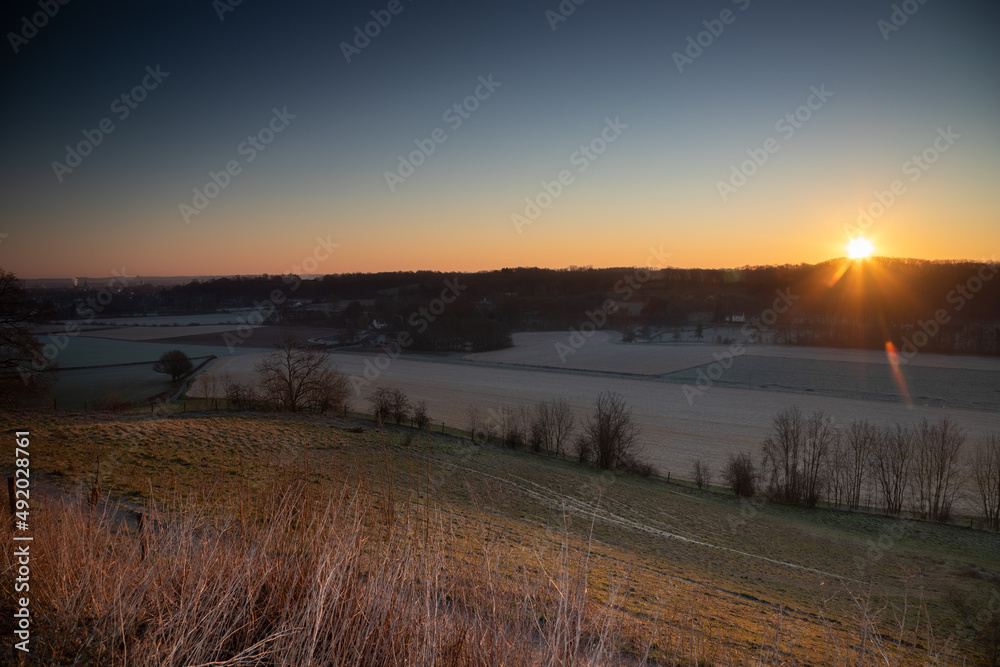 Sunrise over the Jeker valley with the vineyards near Maastricht with a view on the country border and the typical rolling hills landscape which this area is famous for. Sunrise over the Jeker valley with the vineyards near Maastricht with a view on the country border and the typical rolling hills landscape which this area is famous for.
