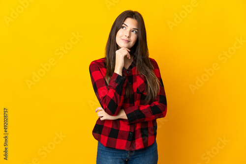 Teenager Brazilian girl isolated on yellow background and looking up