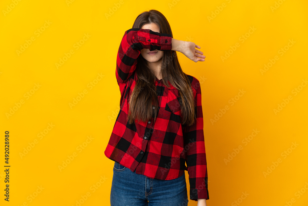 Teenager Brazilian girl isolated on yellow background covering eyes by hands Teenager Brazilian girl isolated on yellow background covering eyes by hands