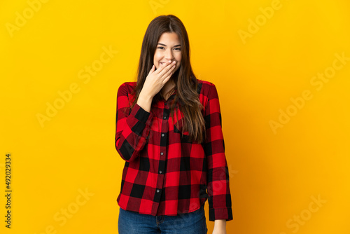 Teenager Brazilian girl isolated on yellow background happy and smiling covering mouth with hand © luismolinero
