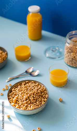 Breakfast concept with cold cereals and orange juice on blue background