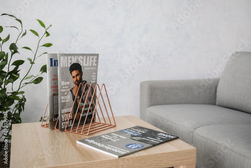 Metal organizer with magazines on table in living room