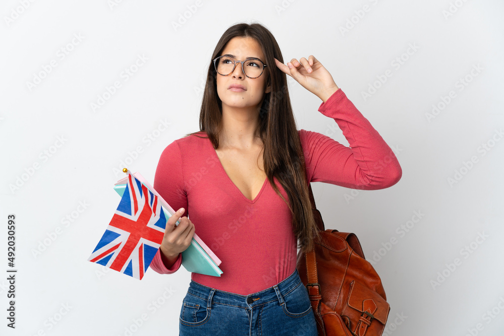 Teenager Brazilian girl holding an United Kingdom flag isolated on white background having doubts and thinking Teenager Brazilian girl holding an United Kingdom flag isolated on white background having doubts and thinking