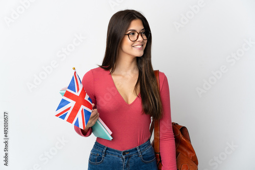 Teenager Brazilian girl holding an United Kingdom flag isolated on white background looking side