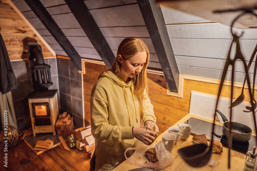Young woman cooking food whilst glamping. Rest in the mountains in Glamping. Cozy fireplace in a mountain house Young woman cooking food whilst glamping. Rest in the mountains in Glamping. Cozy fireplace in a mountain house