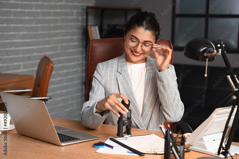 Female notary public attaching seal to document in office Female notary public attaching seal to document in office