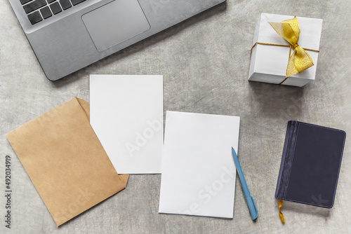 Two A5 postcards on a table with envelope, notebook, notepad, pen and gift box - top view. Blank card mockup