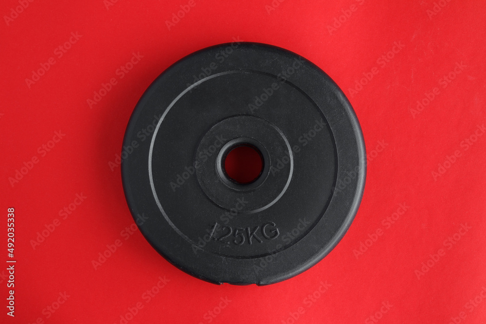 Heavy dumbbells barbell black weight plate. Gym equipment for home workout. Healthy fitness lifestyle flat lay on red background. Heavy dumbbells barbell black weight plate. Gym equipment for home workout. Healthy fitness lifestyle flat lay on red background.