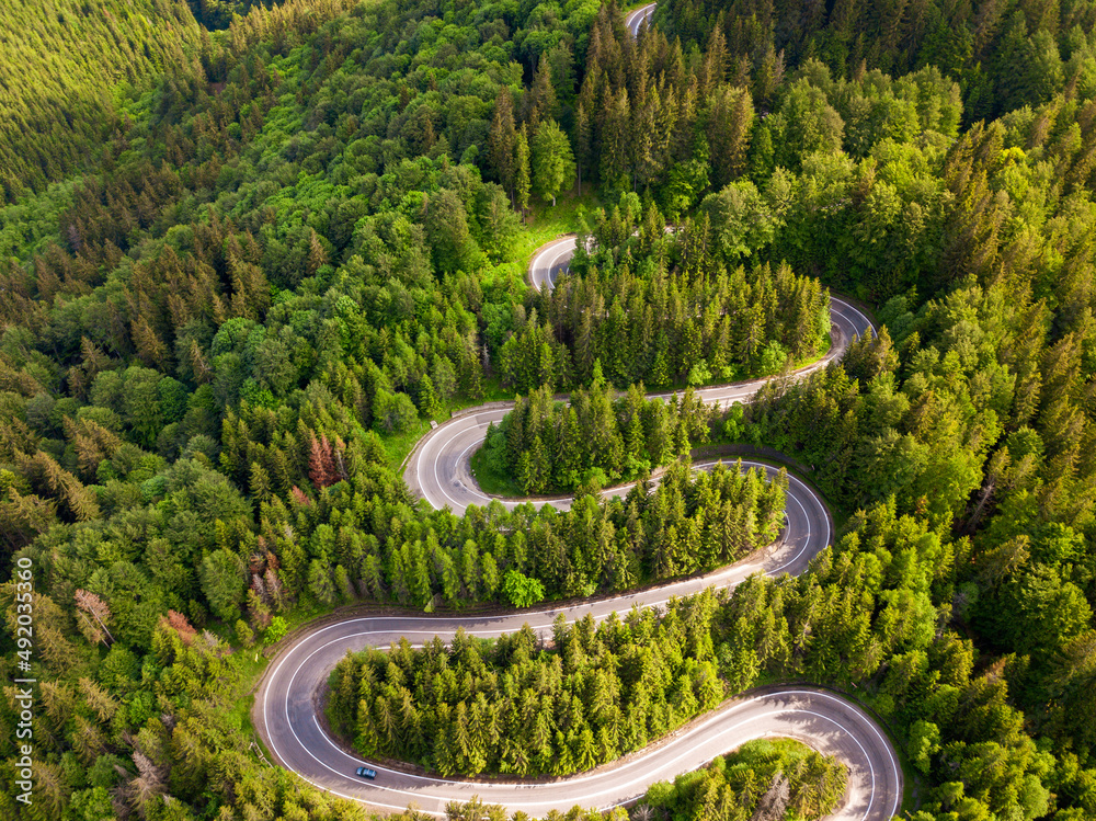 Winding road from high mountain pass, in summer time. Aerial view by drone . Romania Winding road from high mountain pass, in summer time. Aerial view by drone . Romania