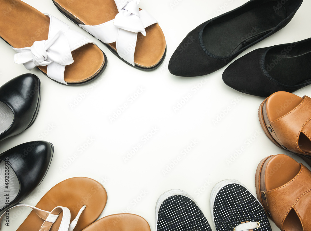 Variety of women's shoes on white background with copy space. Trainers, wedges, flat ballerina shoes or ballet flats, flip-flops thongs, sandals and heels. Variety of women's shoes on white background with copy space. Trainers, wedges, flat ballerina shoes or ballet flats, flip-flops thongs, sandals and heels.