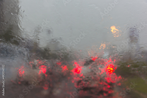 Blurry car silhouette seen through water drops on the car windshield
