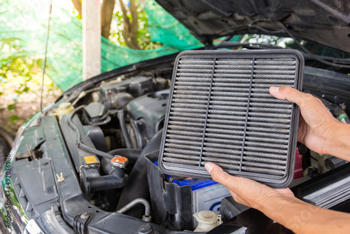 Technician holding dirty air filter for change a new air filter in a car