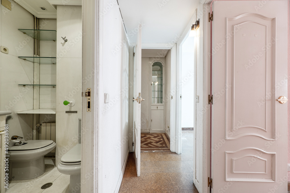 Fototapeta premium Corridor of a residential house with cork floors, access door to a toilet and wood and glass showcase in the background