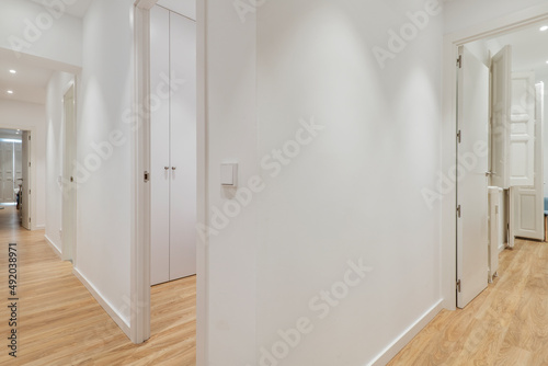 Distributor corridor of a residential house with wooden floors, white wood carpentry in doors and windows and white painted walls © Toyakisfoto.photos