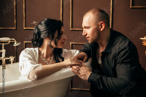 Wife and husband at the photo session in studio. Married bride groom celebrate engagement. Procreation romantic amazing couple indoor, copy space. Preparing for wedding day, lying in bath kissing hugg