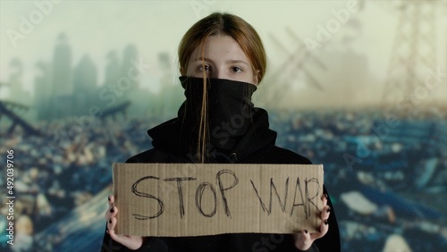 Young woman protesting with cardboard STOP WAR in Ukraine
