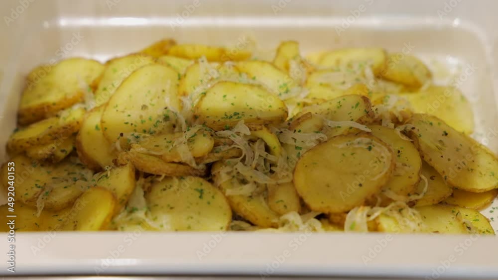 Woman hand open buffet heated trays and Delicious baked round slices of a potato with rosemary in heated serving trays for hotel guests to enjoy a hot meal.
Woman hand open buffet heated trays and Delicious baked round slices of a potato with rosemary in heated serving trays for hotel guests to enjoy a hot meal.