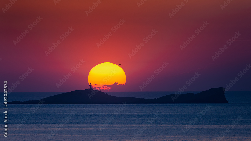 Na Plana lighthouse silhouette in the sun at sunset , Ibiza 