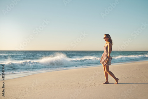 Sometimes the beach is all you need. Shot of a young woman taking a stroll on the beach.